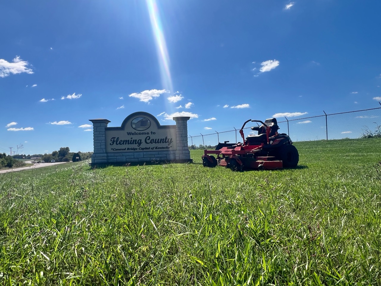Red Gravely zero-turn mower staged beside the Welcome to Fleming County sign