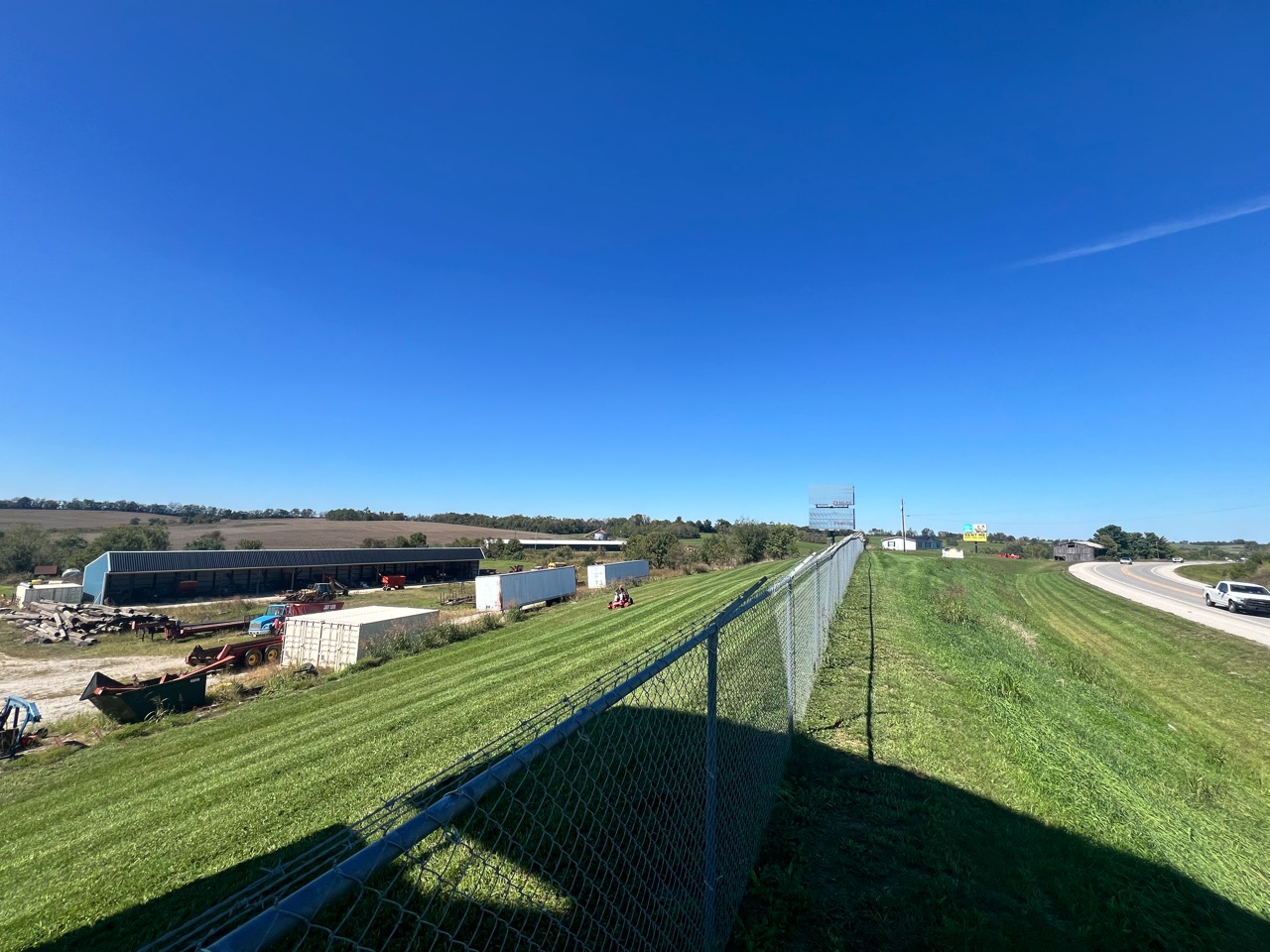 Freshly striped roadside slope running beside a chain-link fence and highway